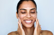 Facial granule scrub and massage. Skin care beauty portrait. Young happy woman is applying peeling cosmetic product to whole her face. Daily skincare routine. Dermatology. Exfoliating