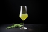 Fototapeta Lawenda - fresh green juice in a wine glass, contrasted against a black backdrop