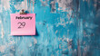 Pink note on blue wall background with written February 29 as a reminder for leap year day with copy space
