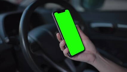 Hand using phone green screen on car, smartphone in hand 