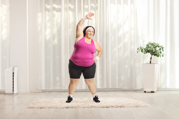 Canvas Print - Corpulent woman stretching arms and exercising at home