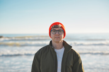 Close up portrait of cheerful attractive young Caucasian man happy smiling face on beach. Male people with cheerful expression looking at camera outdoors. Gen z blonde boy posing natural for photo.