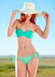 Hat, bikini and woman in nature outdoor for vacation, holiday or summer travel in the countryside by blue sky. Redhead, smile and slim young person in swimsuit, beauty and body health of tourist