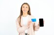 © Jihan - Young beautiful woman holding bank card modern device looking empty space