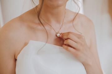 Morning preparation of the bride. Necklace on the neck. Pendant on a gold chain on a woman's breast. Beautiful decollete. Closeup.