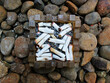 © Zzoe Iggi - Top view of an acrylic ashtray with some cigarette butts in it on the gravel.