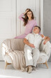 © Anat art - Young happy couple sitting on a sofa in a large studio. Behind them is a large white door. Loving married couple. Cope space for text