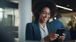 © Larissa - Smiling businesswoman using her phone in the office. Small business entrepreneur looking at her mobile phone and smiling while communicating with her office colleagues.