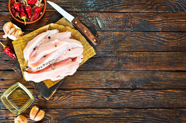 Wall Mural - Raw chicken fillet cut into strips with spices and herbs on a wooden cutting board