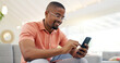 © N F/peopleimages.com - Happy, typing and a black man with a phone on the sofa for social media, connection or communication. Smile, relax and an African person with a mobile for an app, email or notification in a house