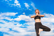 © Алекс Ренко - Slender blonde girl doing yoga outside against a blue sky on a sunny day.