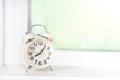 

Spring Time Forward background with Alarm clock with spring flowers on window sills, against sun lighted window.  Spring time, daylight savings concept.  Set your clocks forward an hour. 