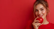 Beautiful smiling woman with a red apple on a red copy space background. Fresh food and healthy lifestyle concept