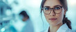 © Synaptic Studio - Young woman researcher. She is wearing a white coat. Medicine and Biology Laboratory behind her and a team of scientists. Research, medicine and healthcare concept.