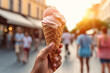 Female Hand Holding Ice Cream Cone in City Street Landscape on Summer Day. Travel Blogger Food Photography with More People in Blur Background