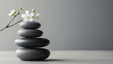 Zen stones stacked with a delicate white flower on top.