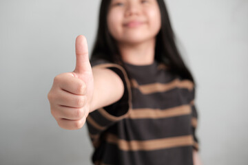 Smiling Cute Little Asian Girl gesturing success with a thumbs-up sign,