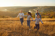 © Studio Romantic - Happy smiling family with two kids daughter and son walking outdoors enjoying beautiful nature. Mother, father with children running outdoors in the field at sunset. Family leisure concept.