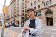 © PhotoBook - Woman student with backpack is standing in front of city building on blurred city background and looking camera