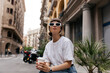 © PhotoBook - Attractive stylish girl with short hair in sunglasses wearing white t-shirt resting outside