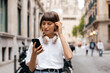 © PhotoBook - Romantic cute woman with short hair is touching her hair and looking at smartphone