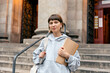 © PhotoBook - Close up portrait of lovely cute girl with notes posing to camera in front of university