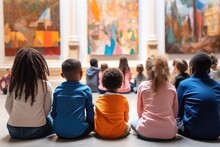 Vertical Back View At Diverse Group Of Children Sitting On Floor In Modern Art Gallery And Listening To Art Expert