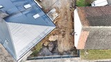 Fototapeta Do akwarium - Roboty ziemne przy budowie drogi między budynkami z kostki brukowej, zdjęcie z drona.