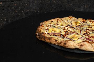 Pizza de manzana al horno con manzanas caramelizada sy queso azul sobre un fondo negro