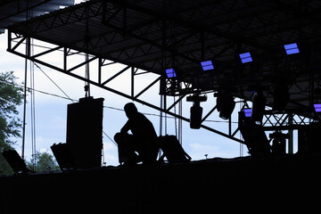 Technician setting up the scenery lights for a stage. Backlit silhouette of scenery.