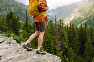 Close-up of female legs in hiking boots on a hiking trail, on top of a mountain outdoors. Travel, vacation.  The concept of nature, relaxation, walking.