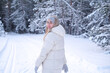 © Viktoriia - A woman in a white jacket and hat standing in the snow