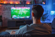 Man watching sports game on tv at home. He is a big fan of sports, so he watches every game on TV. He prefers to watch football. He's chilling.