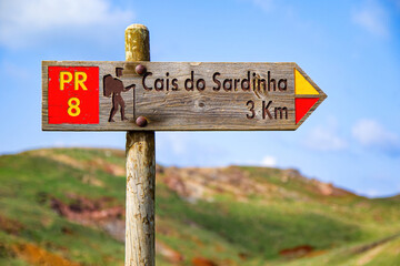 Wall Mural - Wooden signpost pointing at the Cais do Sardinha (sardine pier) on the Ponta de São Lourenço (tip of St Lawrence) at the easternmost point of Madeira island (Portugal) in the Atlantic Ocean