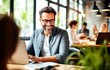 © YannTouvay - Portrait of a smiling young man using laptop while working in office
