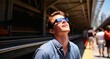 Portrait of a young man in a blue shirt and sunglasses standing on the platform of a subway station