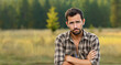 Portrait of a young man in a plaid shirt on a background of nature