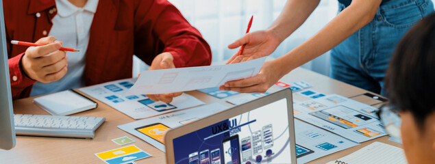 Panorama banner of startup UX developer or company employee design user interface or UI prototype for mobile application or website software with software display on laptop monitor in office. Synergic