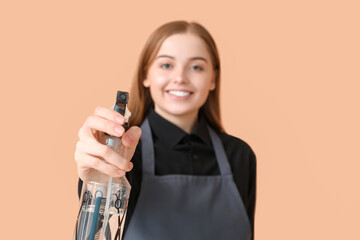 Poster - Female hairdresser with spray on beige background, closeup