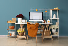 Interior Of Stylish Home Office With Comfortable Workplace, Chrysanthemum Flowers And Pumpkins