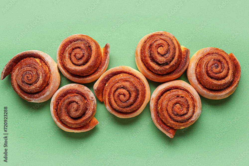 Tasty cinnamon rolls on green background