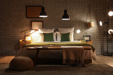 Interior Of Stylish Bedroom With Green Blanket On Bed And Glowing Lamps At Night
