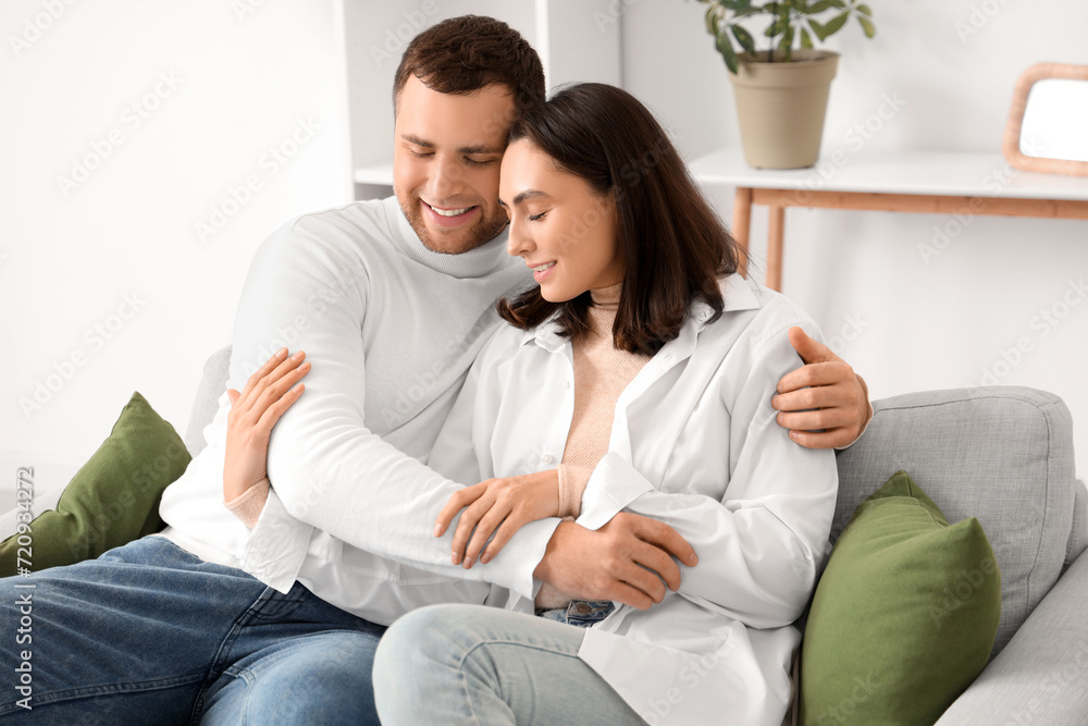 Happy young couple hugging on sofa at home