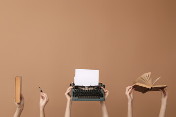 Wall Mural - Women with vintage typewriter and books on brown background