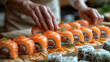 Close-up of female hands decorating sushi roll with salmon.