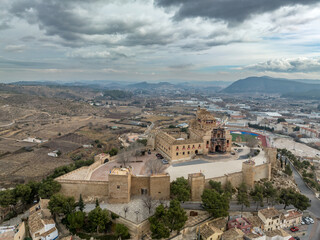 Wall Mural - Aerial view of Caravaca de la Cruz castle dominating the landscape with square and circular towers, medieval palace and Baroque ornament facade church