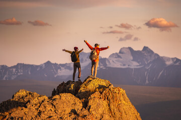 Aufkleber - Two happy young tourists with backpacks are standing with open arms at mountain top and enjoys sunset view