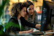 © Chanakan - Focused female colleagues working together on a project using a computer in a vibrant office space.