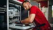 © Phoophinyo - A Side View Young Handyman Repairing Dishwasher, Changing Siphon, Wearing Red Workwear Overalls. Confident Professional Handyman Ar Home ,Focused On Work Alone, In Kitchen.