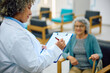 © Drazen - Mature doctor writing medical data of her patient during appointment at medical clinic.